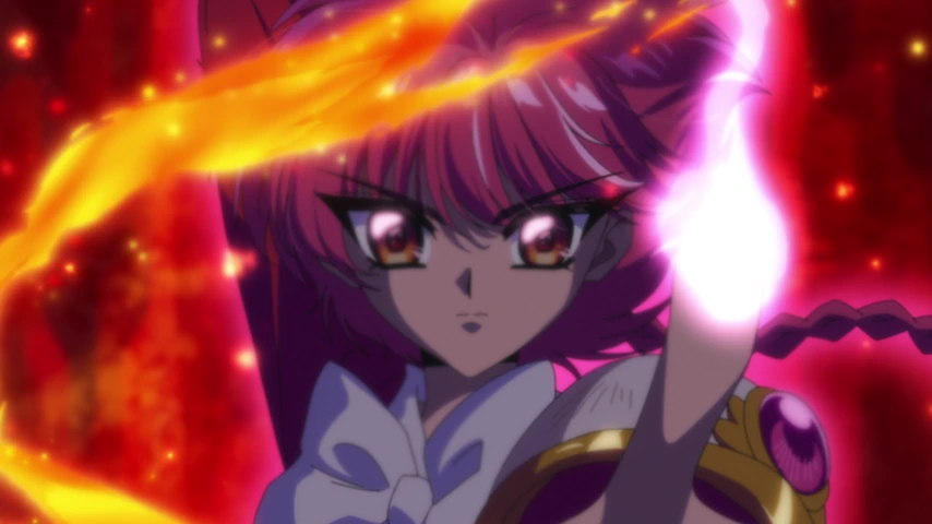 Hikaru aparece em primeiro plano com uma mão erguida diante de uma chama intensa, enquanto Umi e Fuu estão ao fundo.